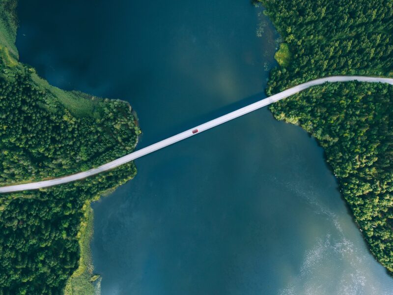 Aerial,View,Of,Bridge,Road,With,Red,Car,Over,Blue