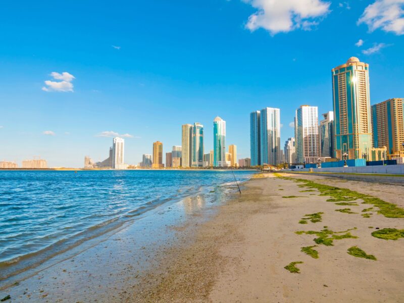 Sharjah,City,Skyline,At,Sunrise,With,Golden,Light,Reflecting,On